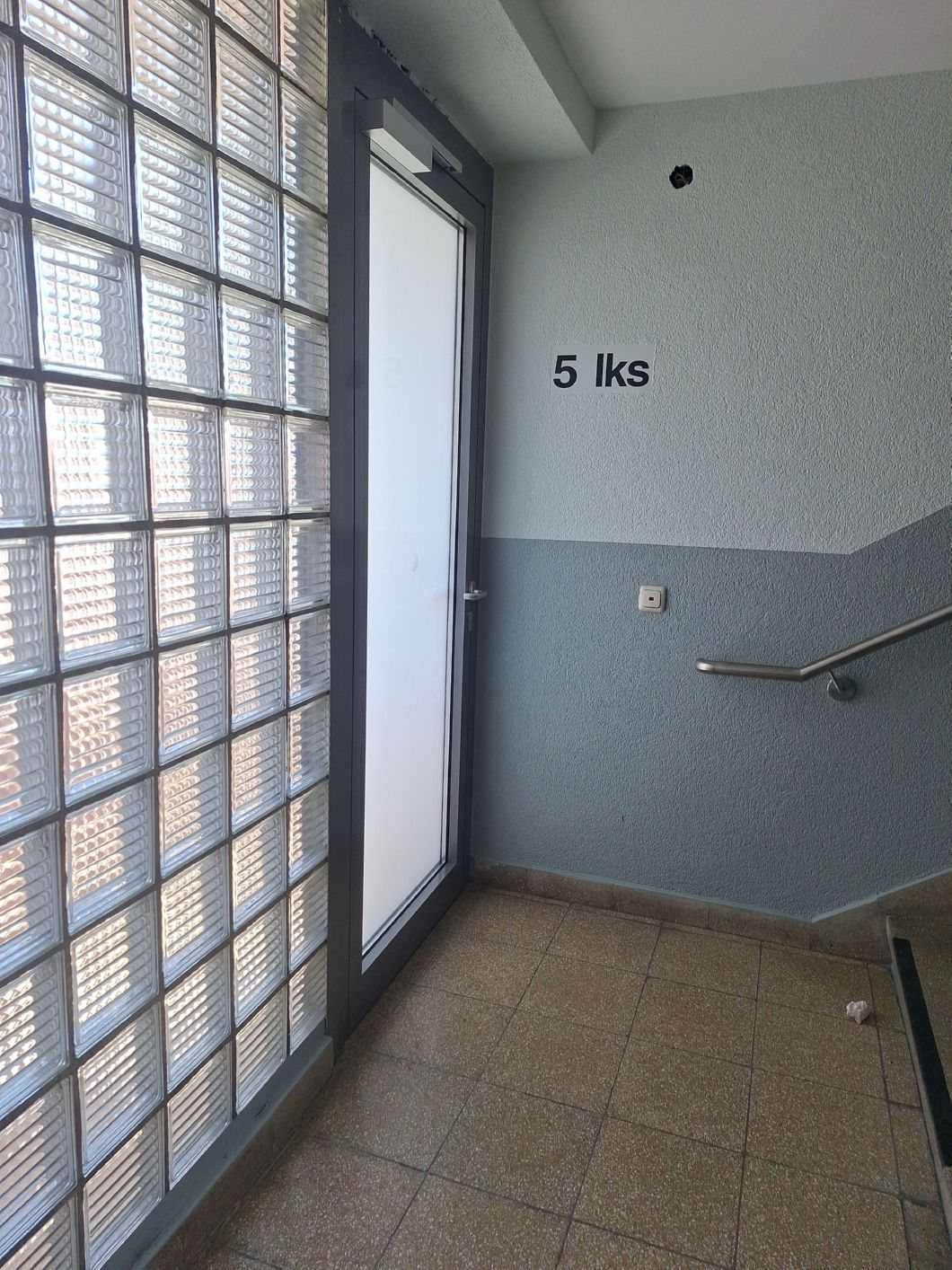 Treppenhaus W&auml;chterstra&szlig;e nach der Sanierung &ndash; neue T&uuml;r und Anstrich in Gr&uuml;ngrau